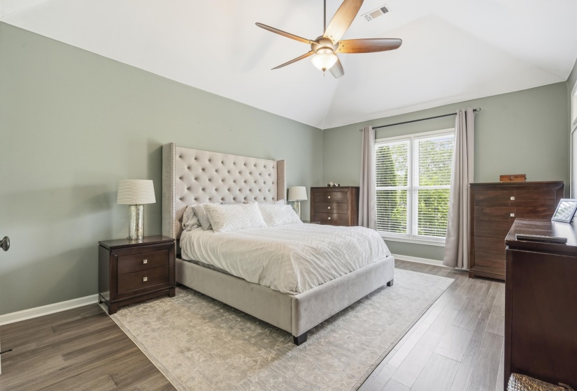 Vaulted ceiling room featuring wood-finish flooring, a large window with blinds, and a ceiling fan with integrated lighting