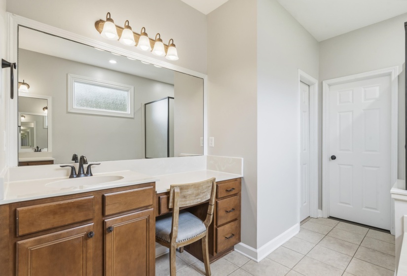 Vanity area featuring an integrated dressing table, wood cabinetry, stone countertops, and bronze-finish fixtures