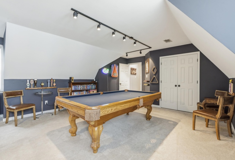 Spacious bonus room featuring an angled ceiling, track lighting, and soft carpet flooring