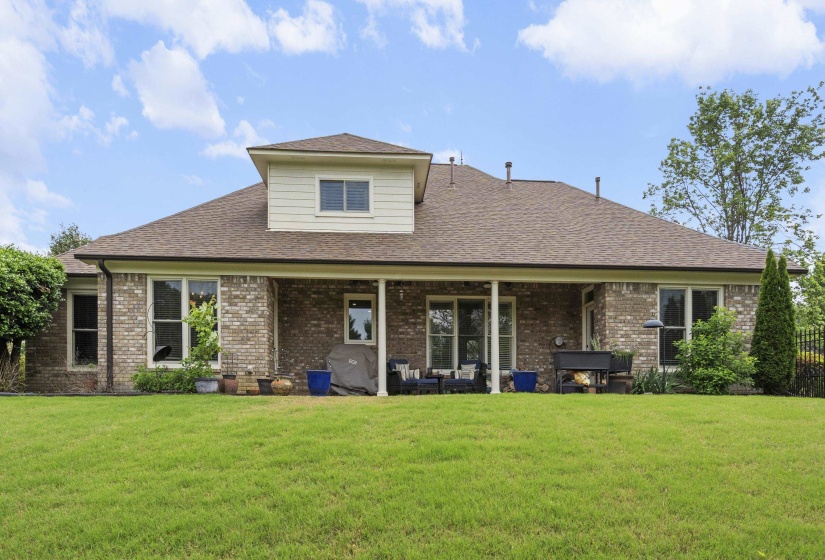 Spacious backyard featuring an extensive lawn and a brick-sided residence
