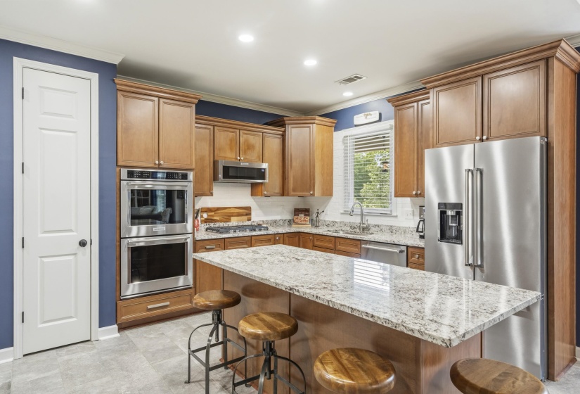 Kitchen featuring wood cabinetry, stainless steel appliances, granite countertops, and an eat-at island
