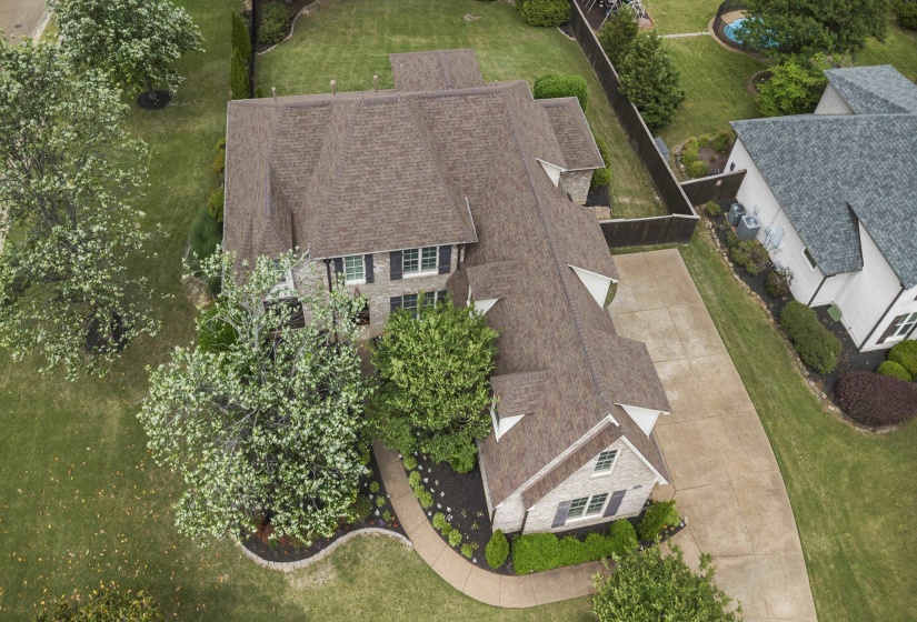 Stately two-story residence featuring a brick facade, dark shingle roof, and contrasting dark shutters