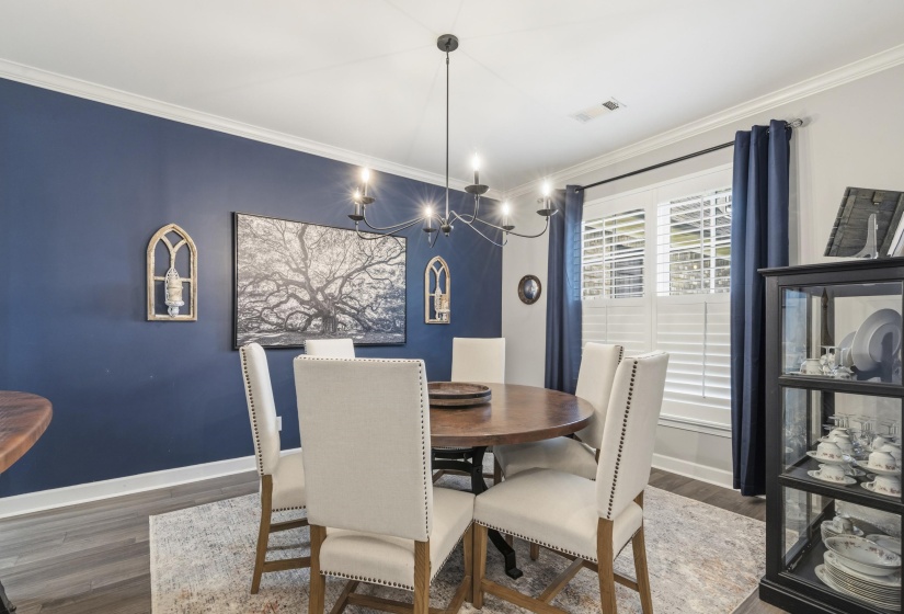Dining area featuring a dark accent wall, crown molding, and wood-finish flooring