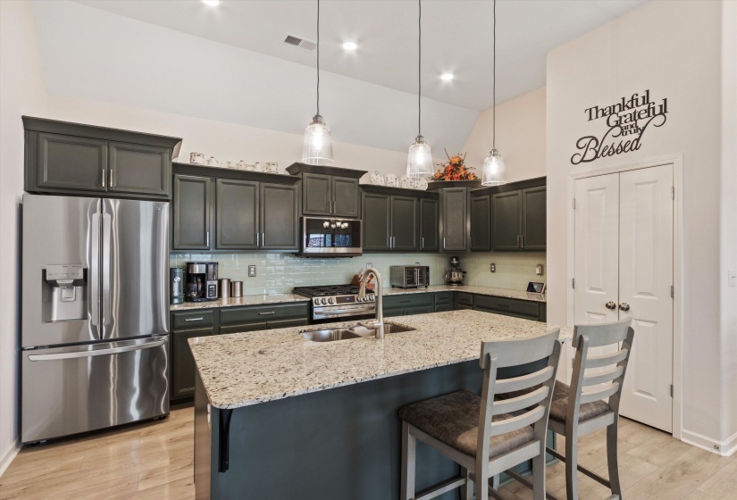 Kitchen features a large island with a built-in dual basin stainless sink, granite countertops, updated matching LG stainless steel appliances, gas range, and a glass tile backsplash.