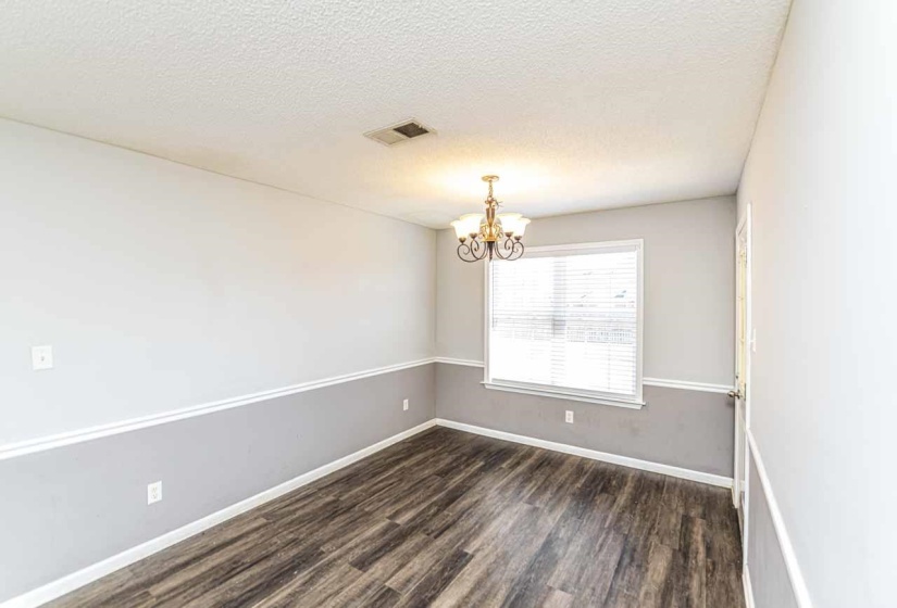 Empty room featuring a textured ceiling, a chandelier, and dark wood-type flooring