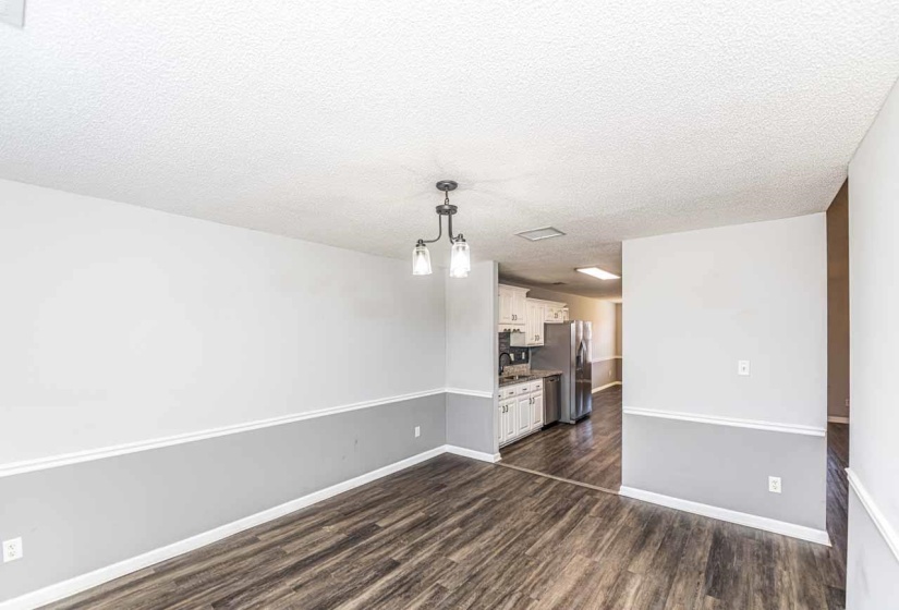 Unfurnished living room featuring a textured ceiling, a chandelier, and dark wood-type flooring