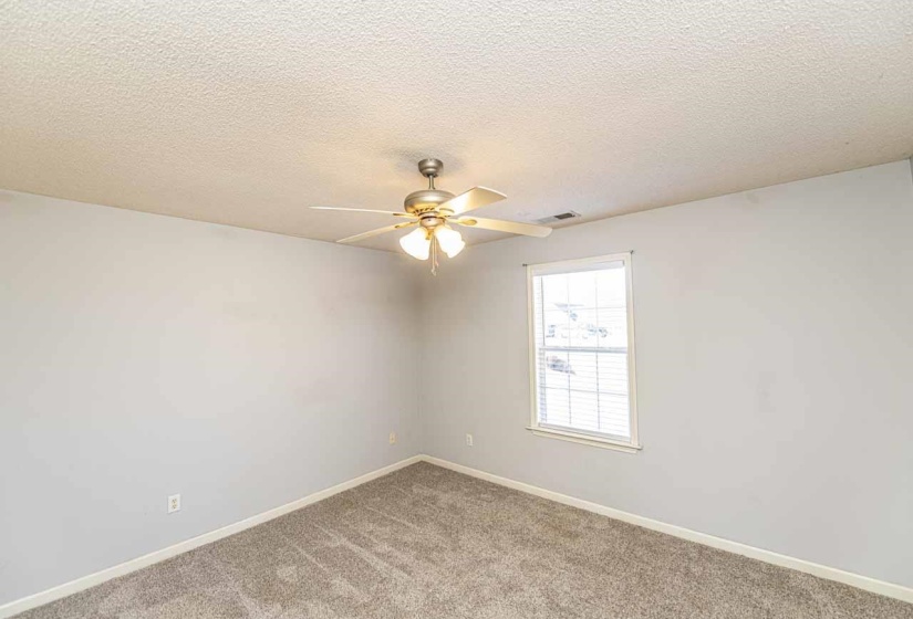 Spare room featuring a textured ceiling, light carpet, and ceiling fan