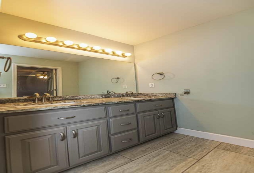 Full bathroom featuring double vanity and baseboards