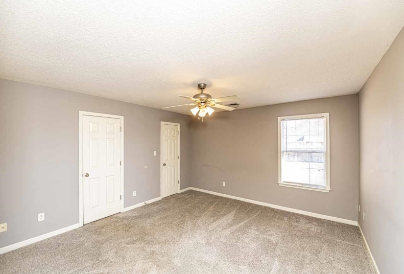 Empty room featuring a textured ceiling, light carpet, and ceiling fan