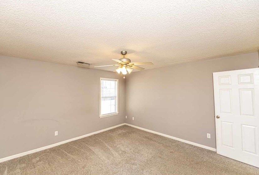 Empty room featuring carpet, a textured ceiling, and ceiling fan