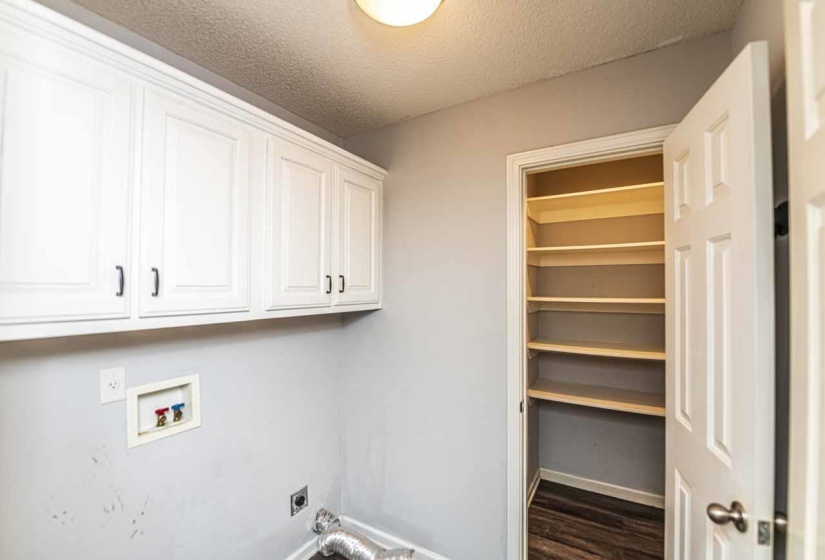 Laundry room with a textured ceiling, hookup for a washing machine, hookup for an electric dryer, cabinet space, and dark wood-type flooring