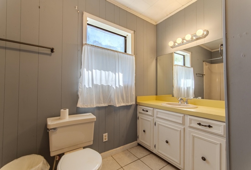 Bathroom with light tile patterned flooring, vanity, wooden walls, curtained shower, and ornamental molding
