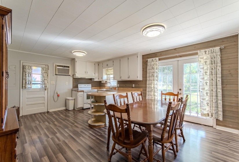 Dining space featuring plenty of natural light, dark wood-style flooring, french doors, a wall mounted air conditioner, and wood walls
