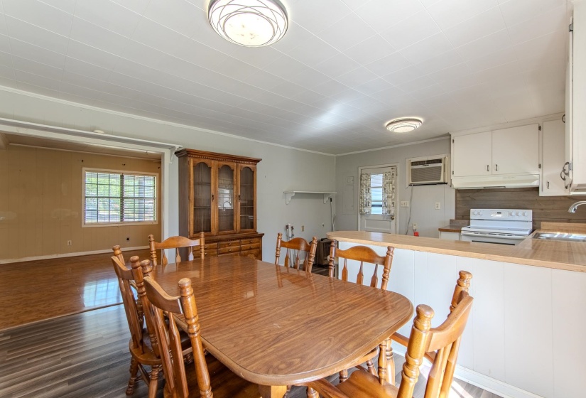 Dining area with light wood finished floors, an AC wall unit, and crown molding