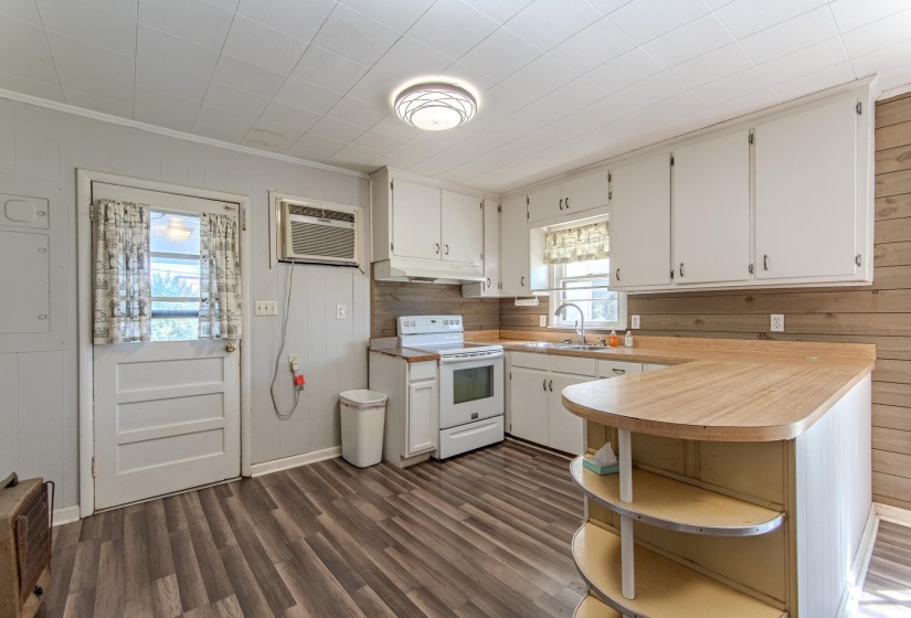 Kitchen featuring wooden walls, light countertops, dark wood-style flooring, electric stove, and white cabinetry
