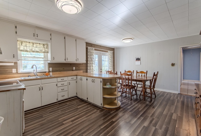 Kitchen featuring a peninsula, light countertops, open shelves, french doors, and dark wood-type flooring