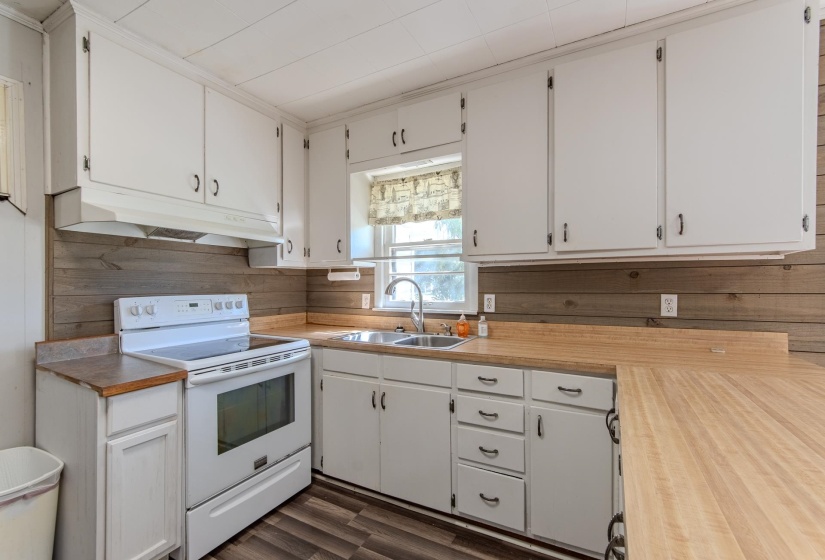 Kitchen featuring electric stove, white cabinetry, light countertops, under cabinet range hood, and dark wood finished floors