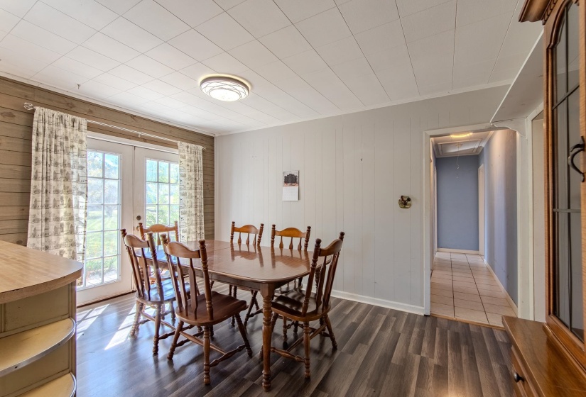 Dining room with dark wood-style floors, wood walls, french doors, attic access, and crown molding