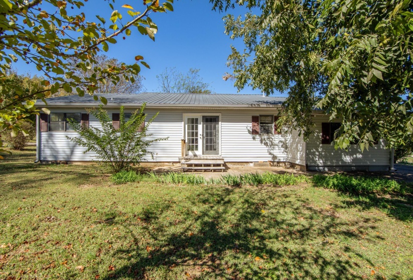 Back of house with a yard, french doors, and a metal roof