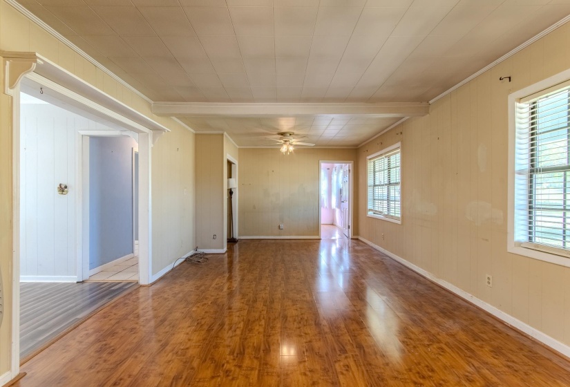 Empty room with wood walls, wood finished floors, crown molding, and ceiling fan