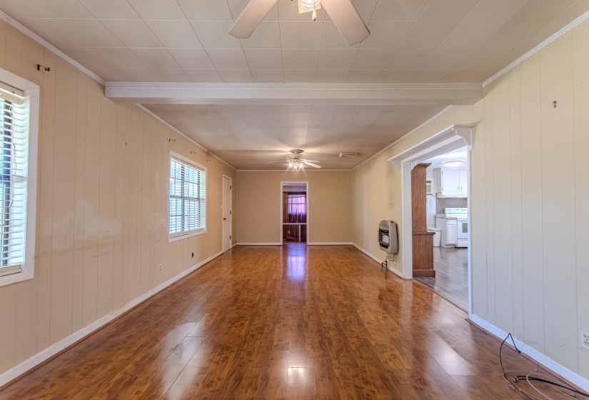Unfurnished room with wooden walls, a ceiling fan, wood finished floors, crown molding, and heating unit