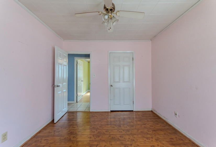 Empty room featuring wood finished floors, crown molding, and ceiling fan