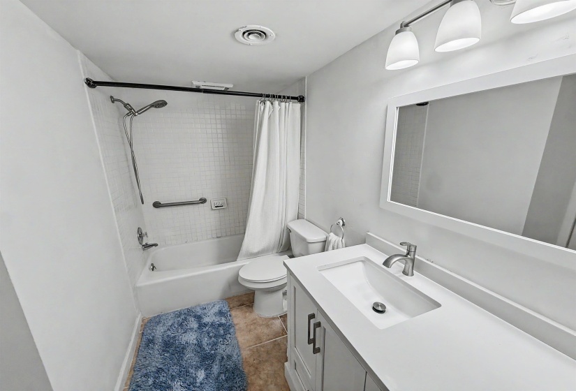 Bathroom featuring a white vanity with integrated sink and brushed nickel faucet, framed mirror, and three-light fixture