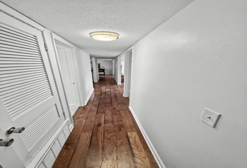 Long hallway featuring wood-finish flooring, white walls, and a flush-mount ceiling light fixture
