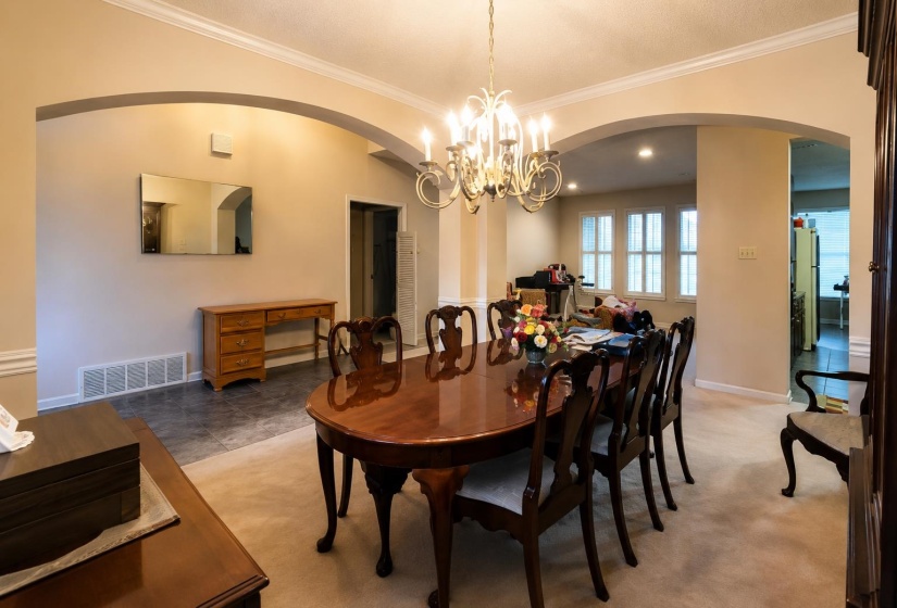 Formal dining area featuring a prominent chandelier, crown molding, and arched doorways
