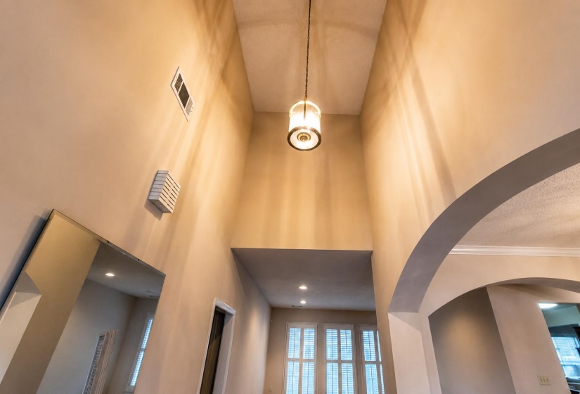 Inviting foyer with vaulted ceiling with a suspended drum pendant light