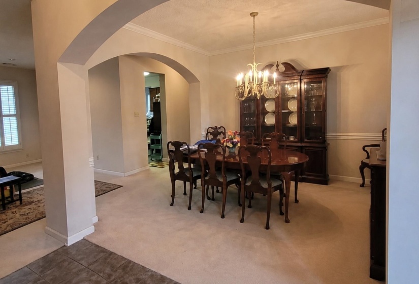 Spacious dining area featuring an ornate chandelier, crown molding, and wainscoting