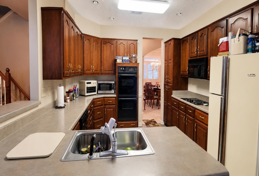 Kitchen featuring wood-finish cabinetry, solid surface countertops, and a double wall oven