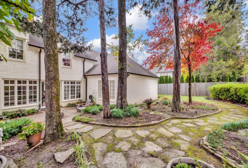 Serene backyard oasis with mature trees, lush landscaping, and picturesque stone pathways.