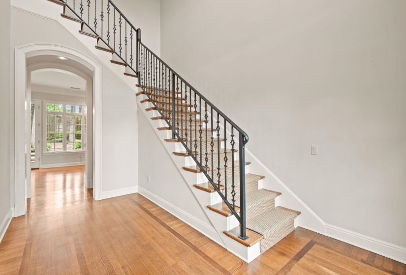 Elegant staircase featuring wrought iron balusters, rich wood treads, and a classic carpet runner.