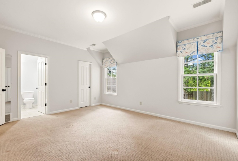 Inviting secondary suite upstairs featuring soft carpeting, abundant natural light from multiple windows, crown molding, charming architectural details, and a private en suite bathroom.