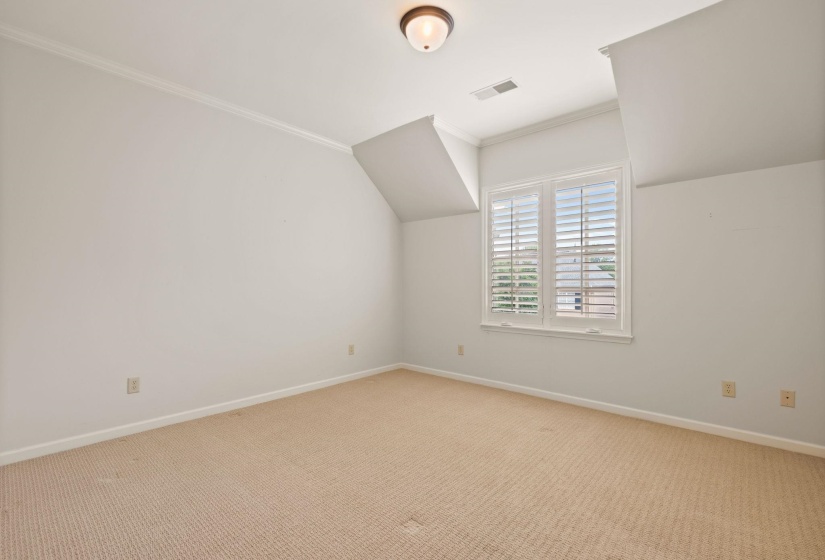Upstairs bedroom with plush carpeting, bright and airy with multiple windows, architectural angled ceilings, a spacious closet, and private access to a shared full bathroom.