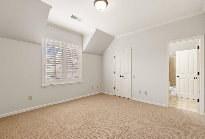 Second upstairs bedroom with plush carpeting, bright and airy with multiple windows, architectural angled ceilings, a spacious closet, and private access to a shared full bathroom.