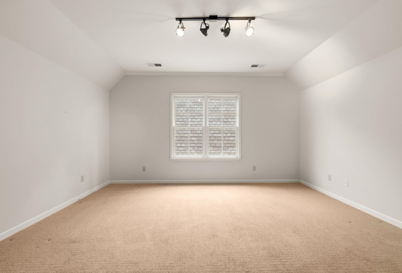 Versatile upstairs bedroom or bonus room with abundant natural light, flexible space for a home office, gym, or guest retreat, and access to a floored walk-in attic for added storage.