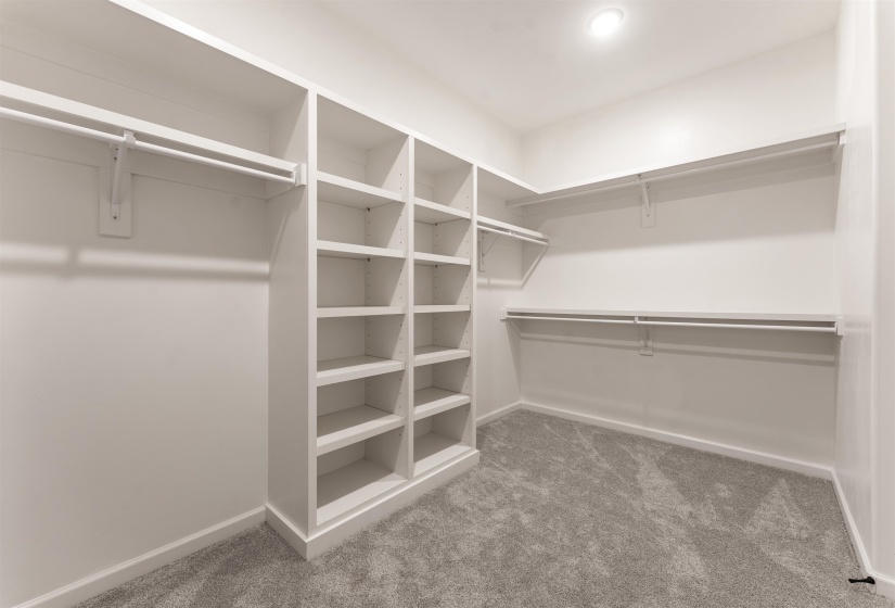 Spacious walk-in closet featuring built-in shelving, multiple hanging rods, and recessed lighting