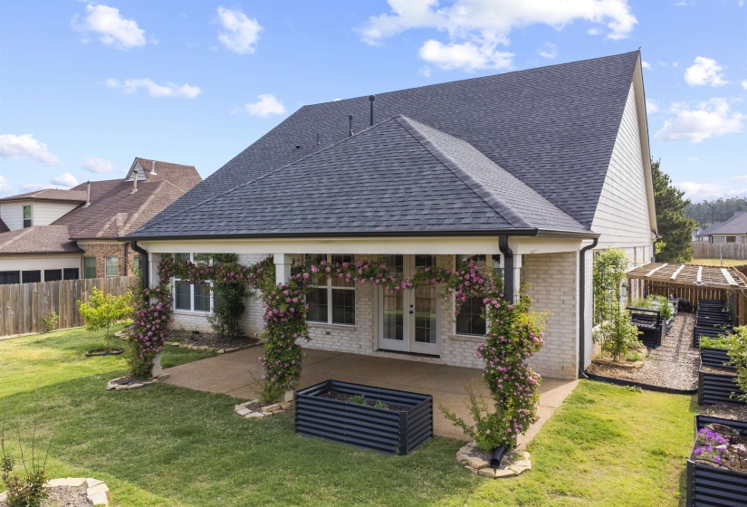 Rear exterior featuring a covered patio, double French doors, and white brick siding
