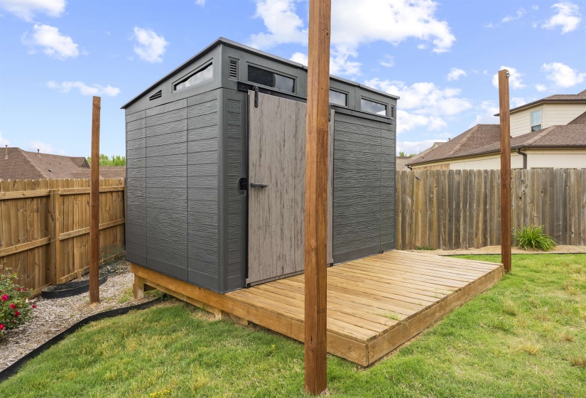 Detached storage shed featuring a dark grey exterior, clerestory windows, and a sliding wood-look door