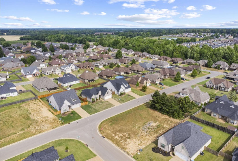 Aerial perspective showcasing a residential development with numerous single-family homes, mature perimeter tree lines, and paved streets