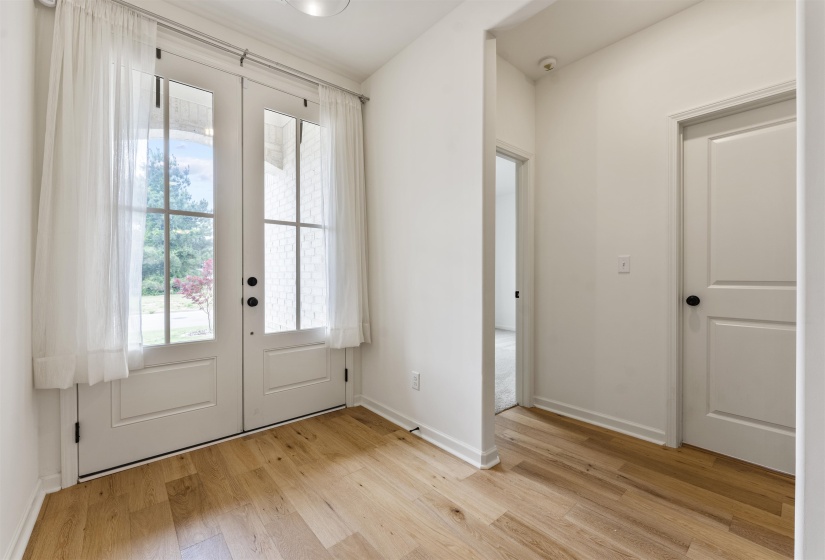 Entryway featuring double French doors with glass panels, light wood-finish flooring, white baseboards, and bright white walls