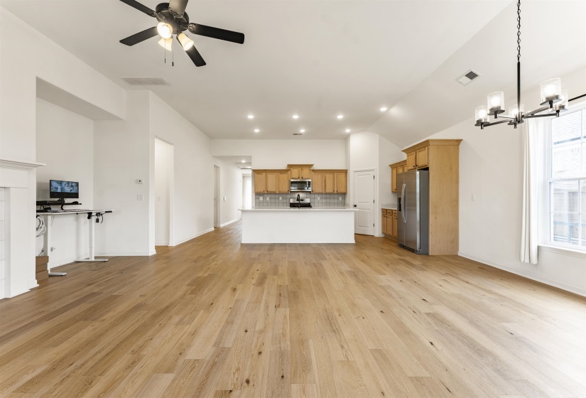 Open-concept living space featuring wood-finish flooring, a contemporary ceiling fan, and a kitchen with light wood cabinetry and stainless steel appliances