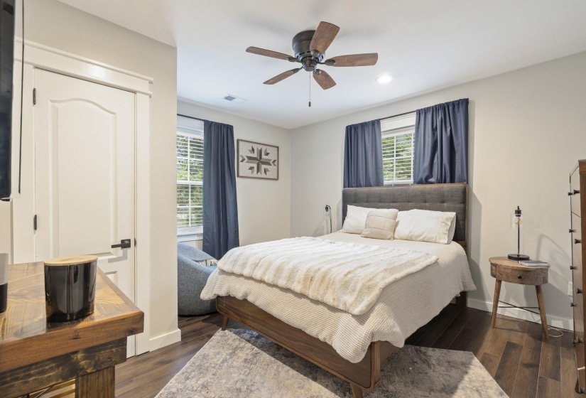 Bedroom featuring wood-finish flooring, a ceiling fan with integrated lighting, recessed lighting, and a white paneled door with matte black hardware