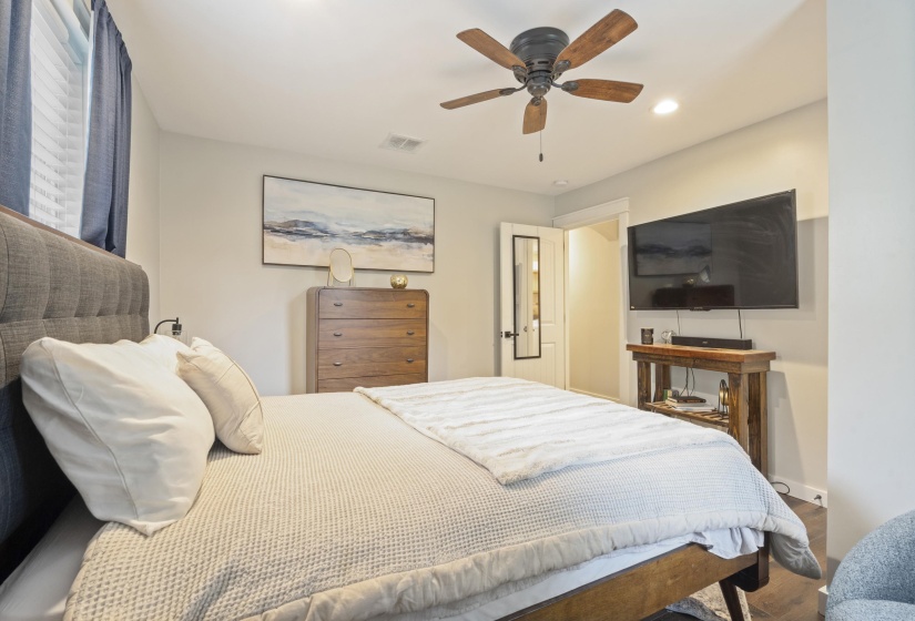 Bedroom featuring wood-finish flooring, a ceiling fan with light, recessed lighting, and a white paneled door with a full-length mirror