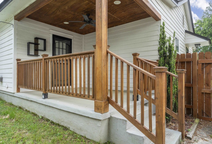Inviting front porch featuring a wood-finish ceiling with an integrated ceiling fan, white siding, and rich wood-tone railings and posts
