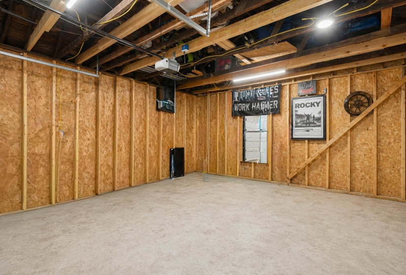 Unfinished basement with exposed ceiling joists and wood-paneled walls