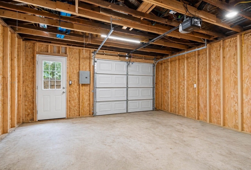 Spacious garage with exposed wood framing and a concrete floor