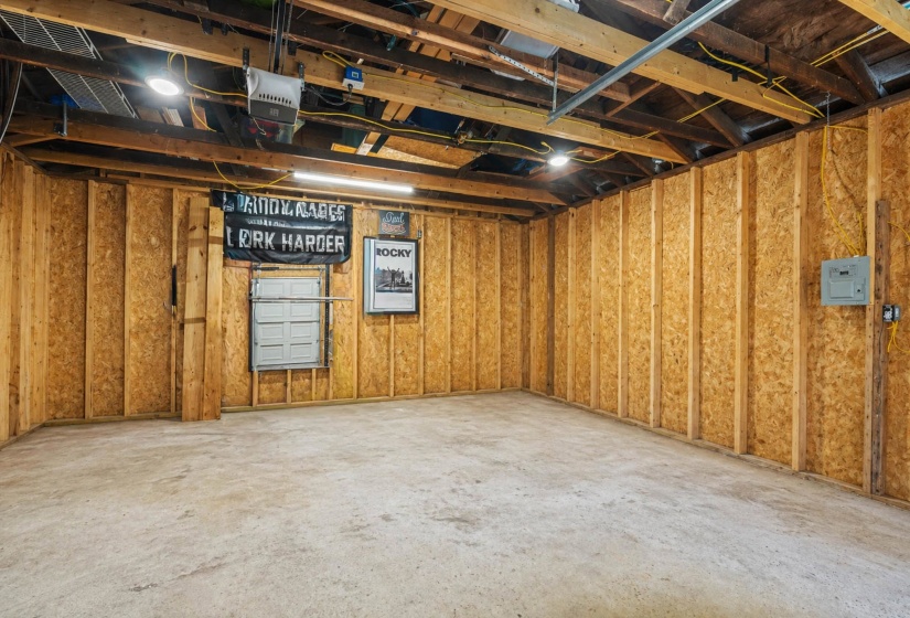 Spacious unfinished garage featuring exposed wooden beams and concrete flooring
